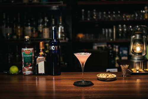 バーカウンターに置かれたピンク色のコスモポリタンカクテル