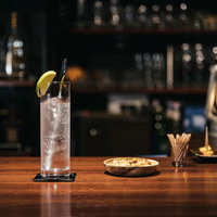 バーカウンターに置かれたオレンジ飾りのジントニックの写真