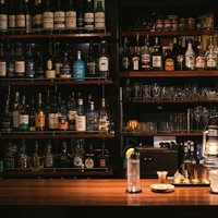 二人分のカクテルやおつまみが並んだおしゃれなバーのカウンターの様子の写真