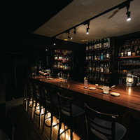 ほのかにライトアップされた暗いカウンターバーの店内の写真