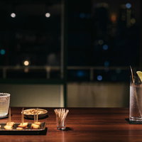 夜景の見えるテラスの窓を背景にカウンターでしっぽりと飲むの写真