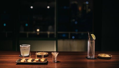 夜景の見えるテラスの窓を背景にカウンターでしっぽりと飲む