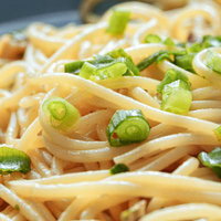 わけぎが散らされたスパゲティパスタ。クリーム色の麺の写真