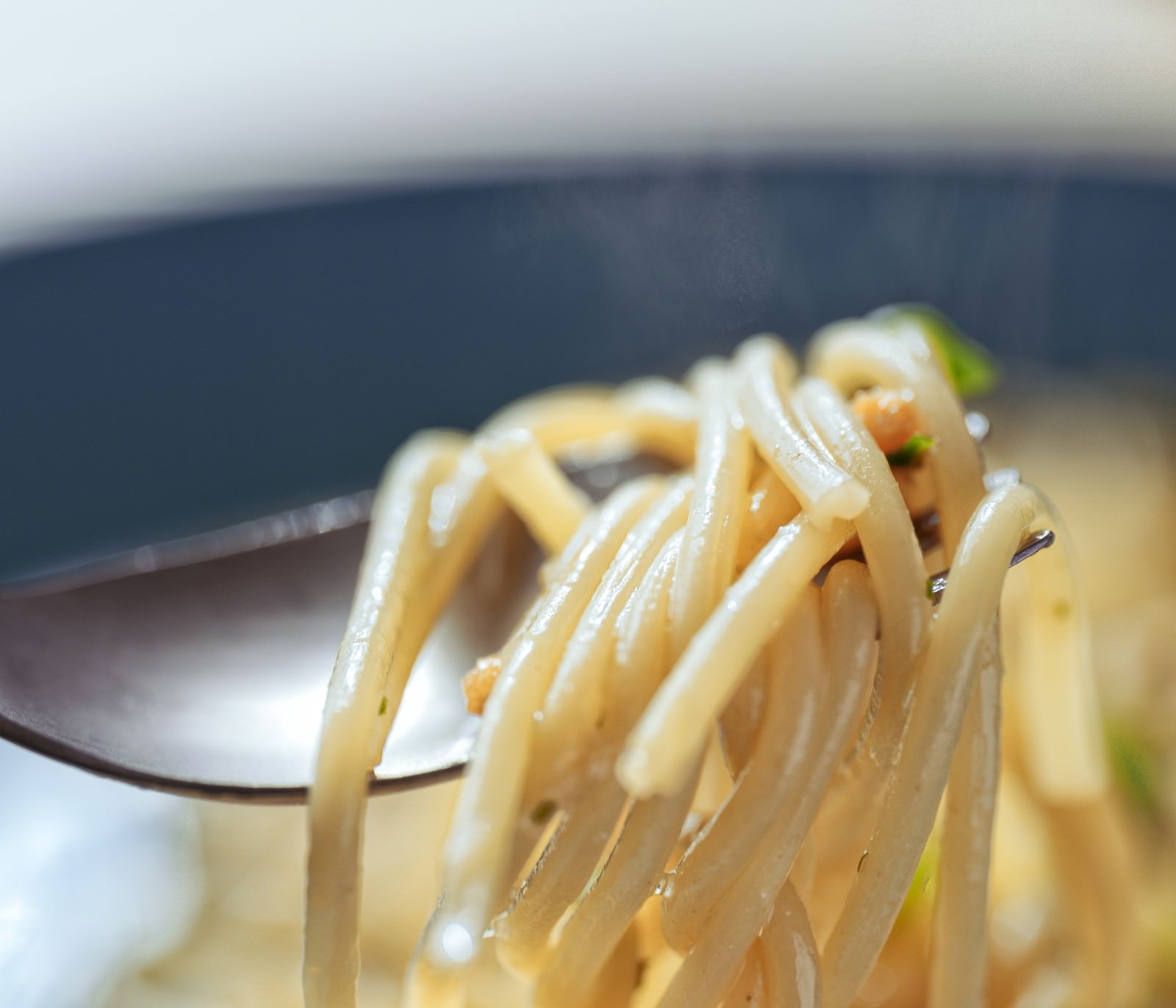 フォークに絡まった温かいパスタから湯気が立ち上る様子