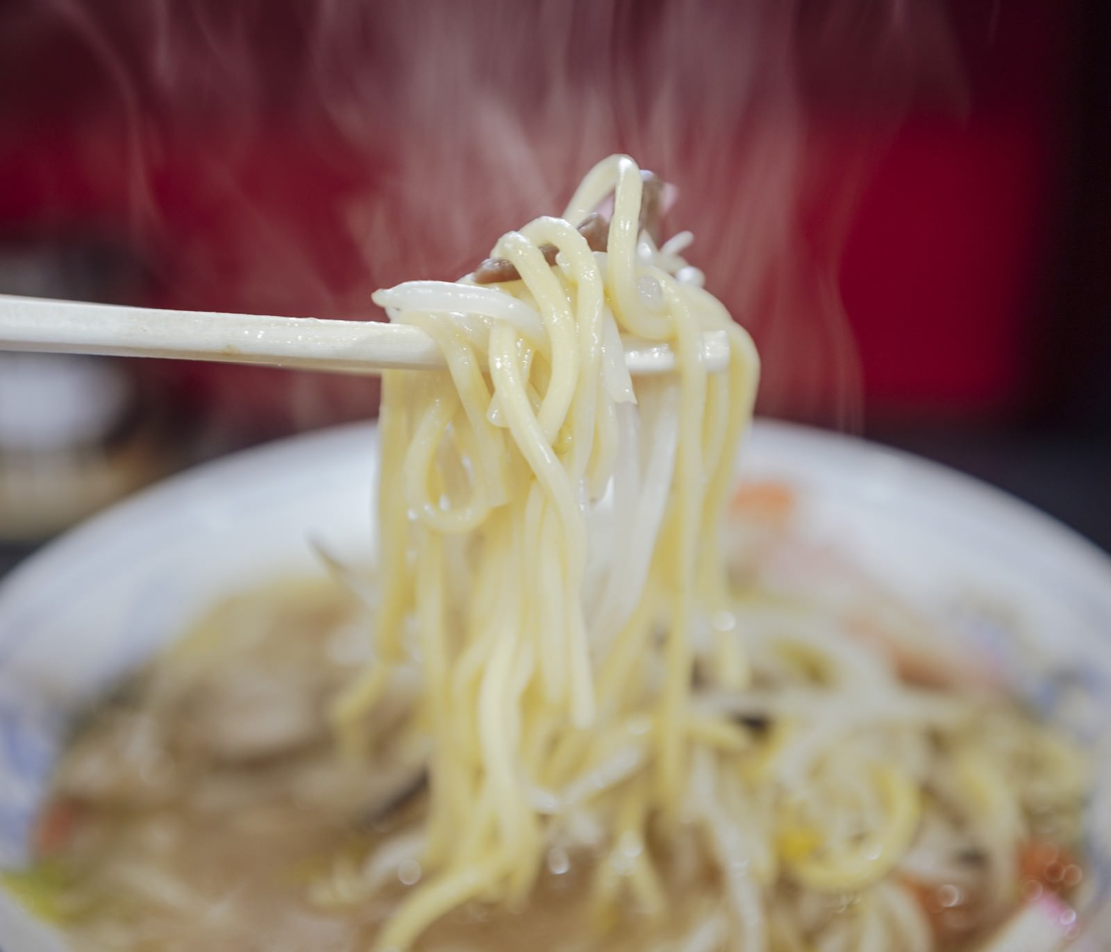 箸で持ち上げられた湯気立つタンメンの麺ともやし