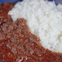 青いお皿に盛られたひき肉カレーとライス、玉ねぎトッピングの写真