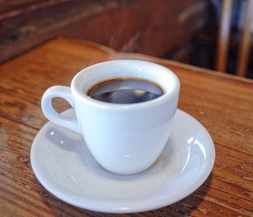 木製テーブルに置かれた淹れたてコーヒーとコーヒー豆