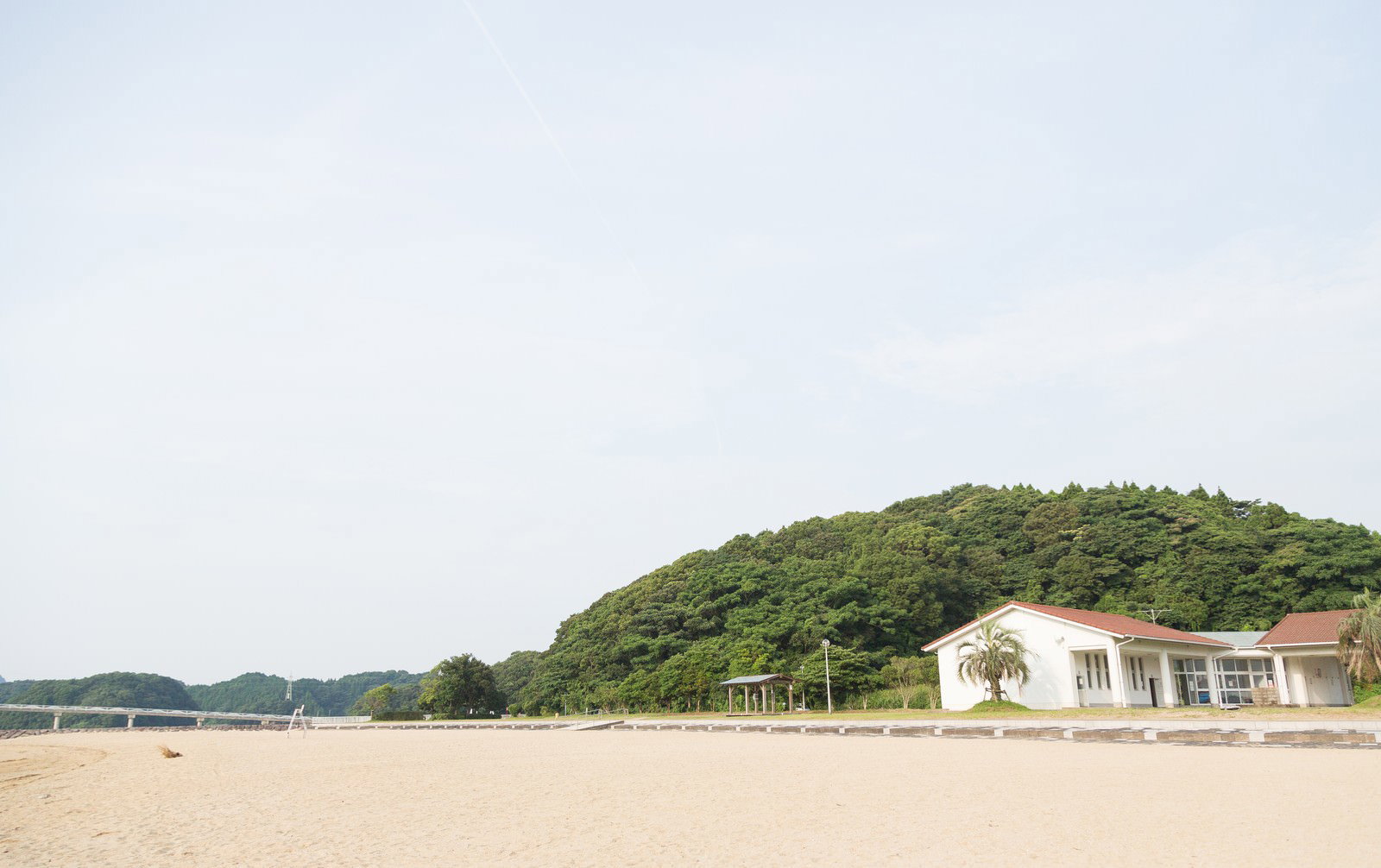 伊万里人工海浜公園の砂浜に立つ白い建物と緑の山