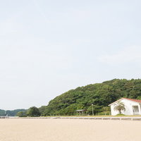 緑の山並みを背景にした伊万里人工海浜公園の砂浜の写真
