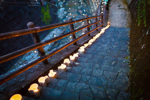 夜間の石段階段に一列に置かれた白い灯ろうのライトアップ風景