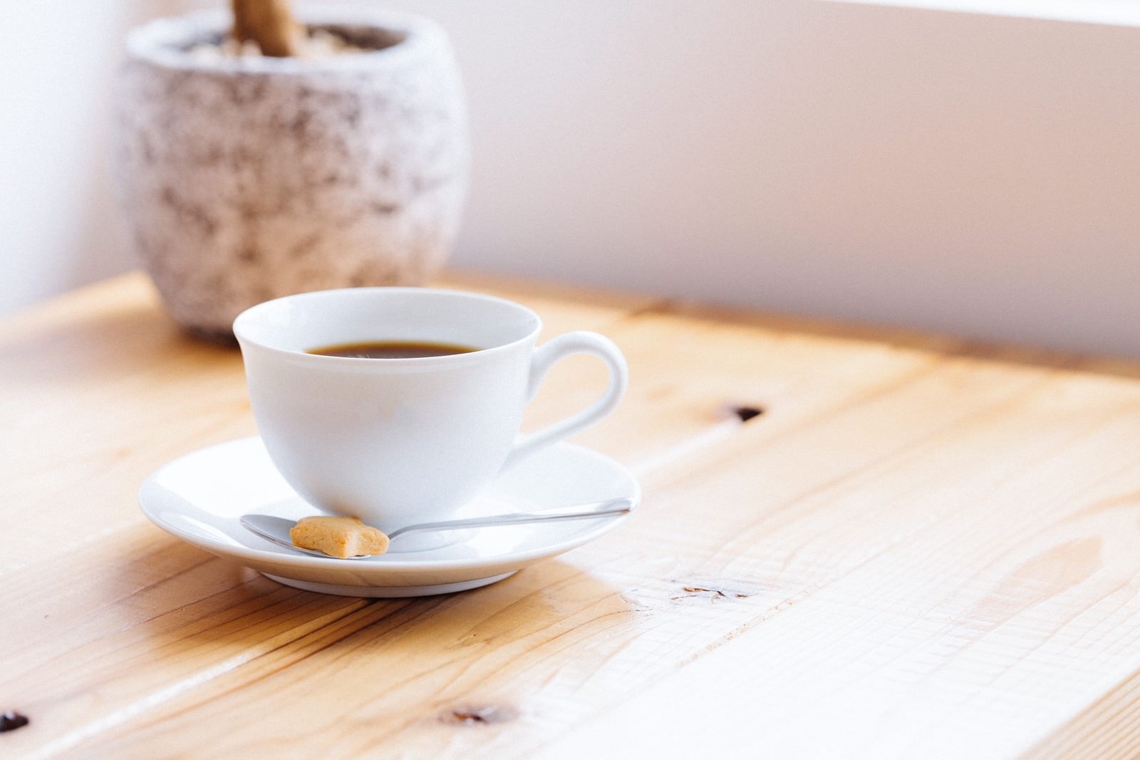 白いカップのコーヒーと受け皿のビスケット