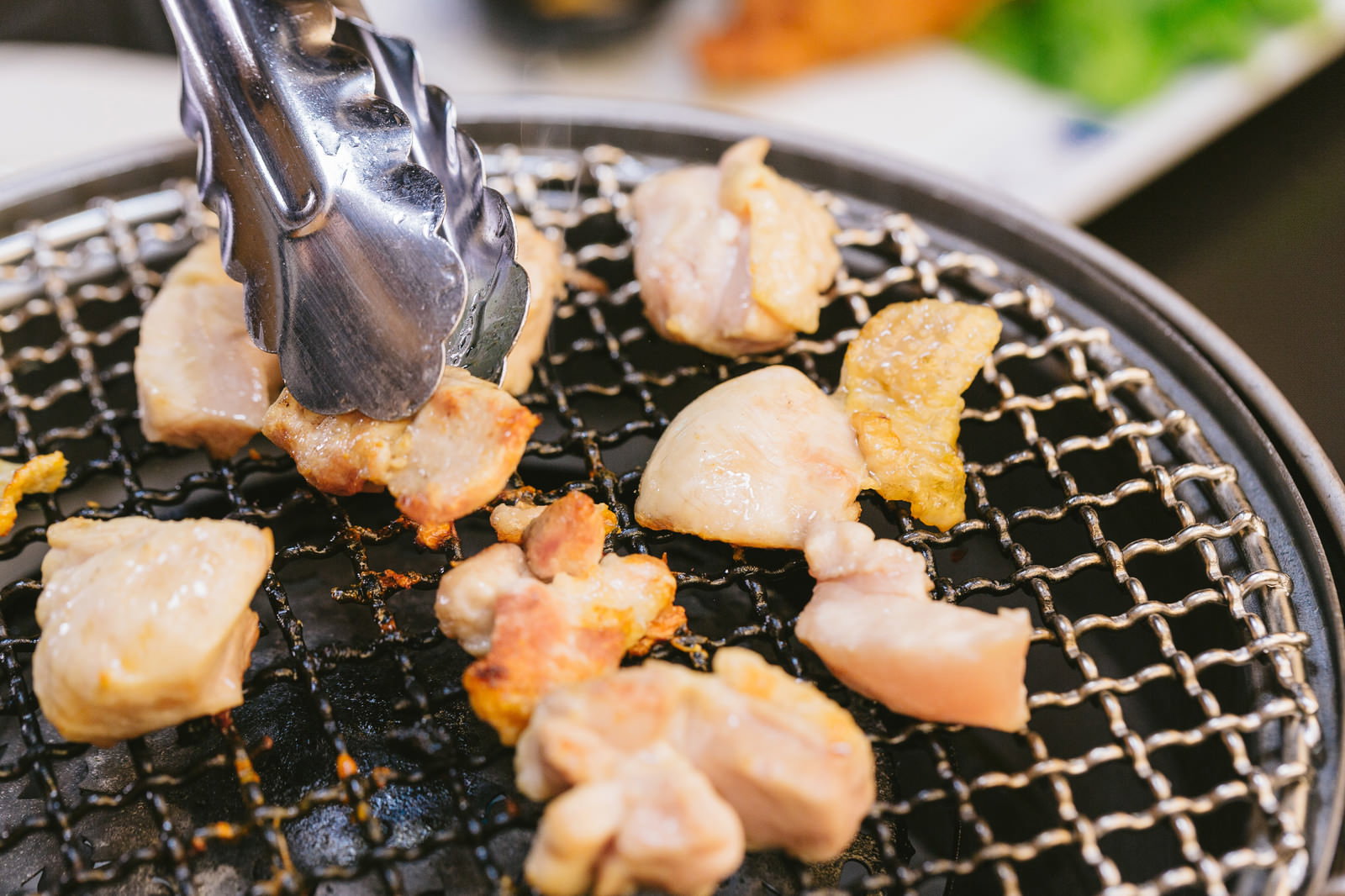 焼き網の鶏肉をトングで返している調理風景