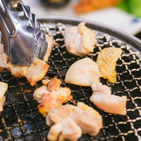 佐賀県伊万里市のドライブイン鳥で鶏肉を網焼きしトングで返す調理風景の写真