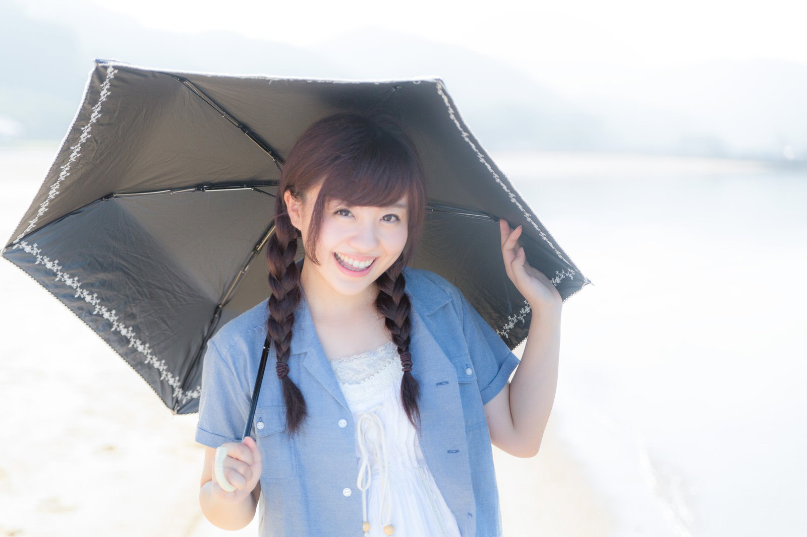 イマリンビーチで日傘を差すおさげの女性［モデル：河村友歌］