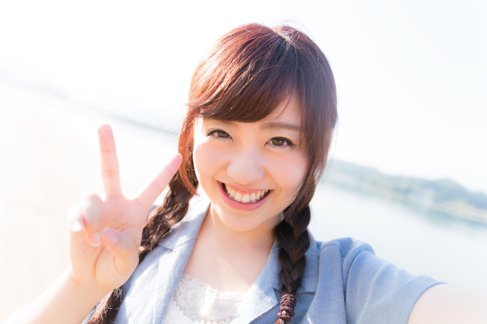 イマリンビーチでピースをして笑う女性の自撮り［モデル：河村友歌］