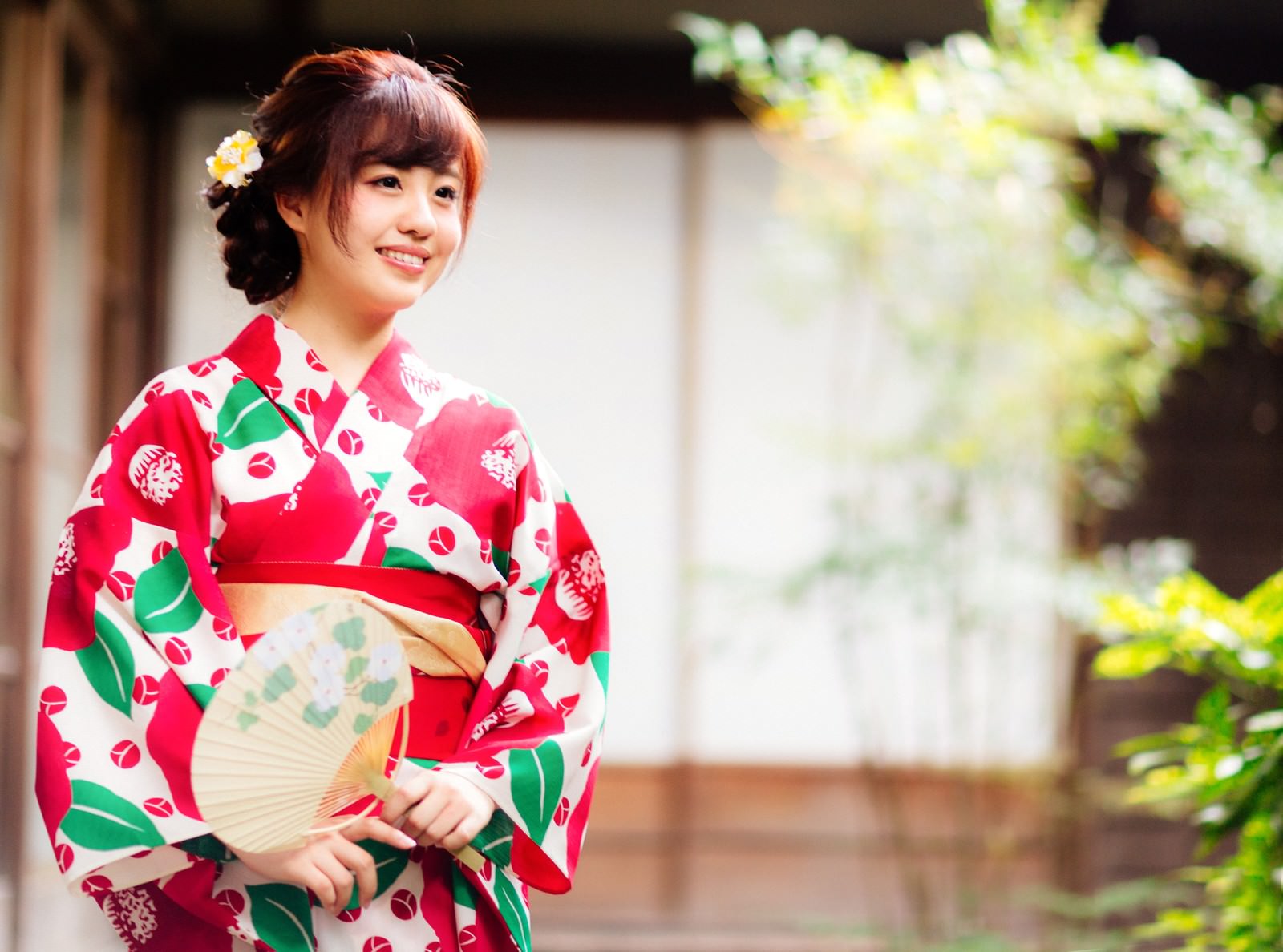 赤い花柄の浴衣を着て団扇を持つ笑顔の女性［モデル：河村友歌］