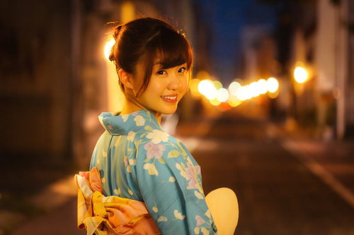 夜間の街並みで振り返る浴衣姿の女性、祭りデート帰り道