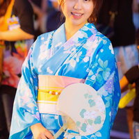 浴衣姿で祭りを楽しむ女性とうちわの写真