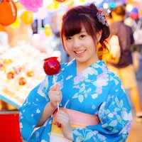 お祭りの屋台でりんご飴を買ってもらった浴衣女子の写真