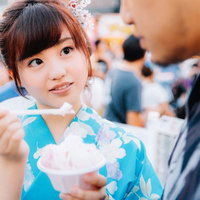 夏祭りの屋台でかき氷を食べる浴衣姿の女性の写真