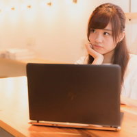 SNSで流れてきた商品をポチろうか悩んでいる女子、頬杖をついて考えるの写真