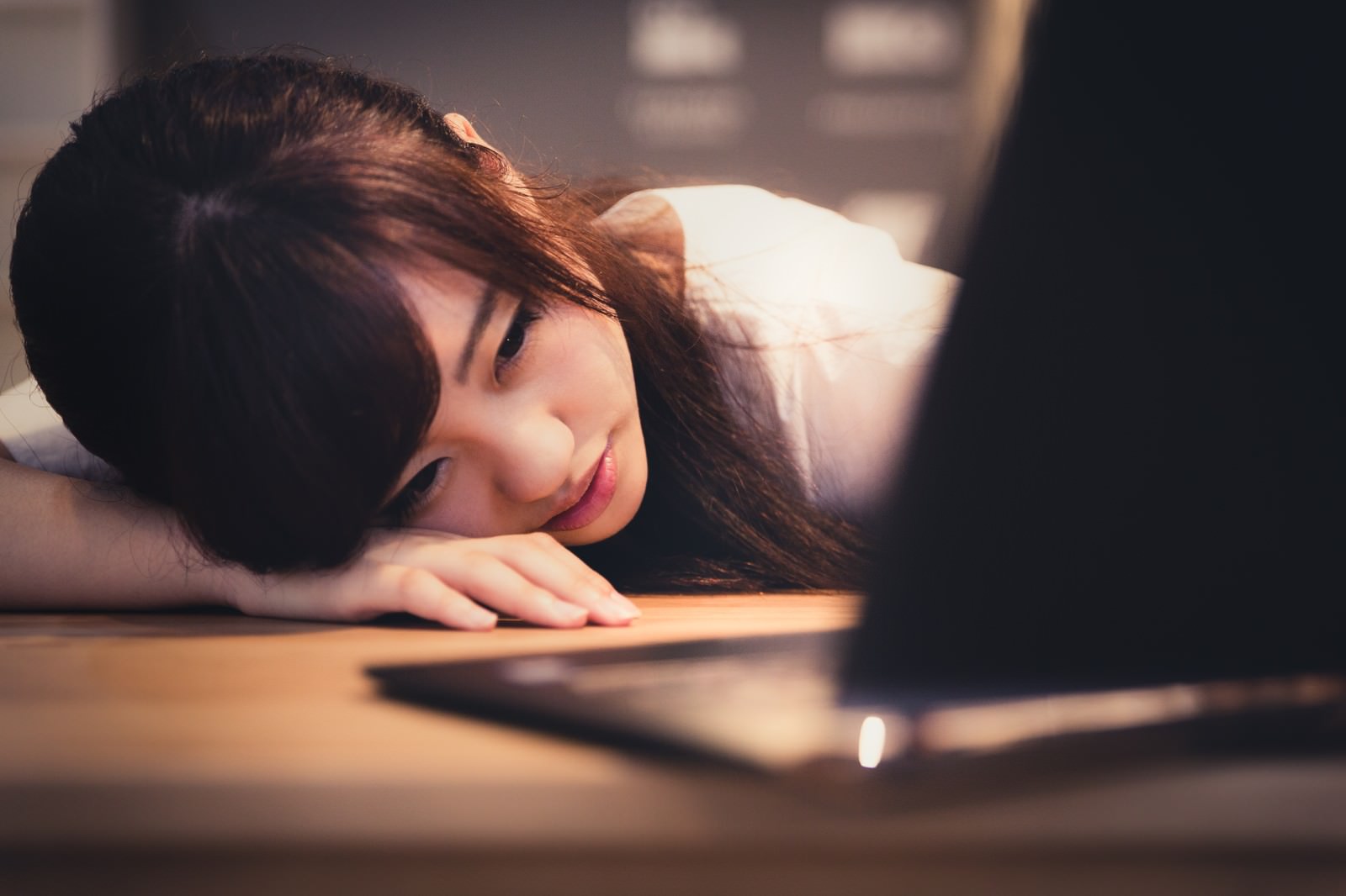 データ消失に落ち込みテーブルにうなだれる女性［モデル：河村友歌］