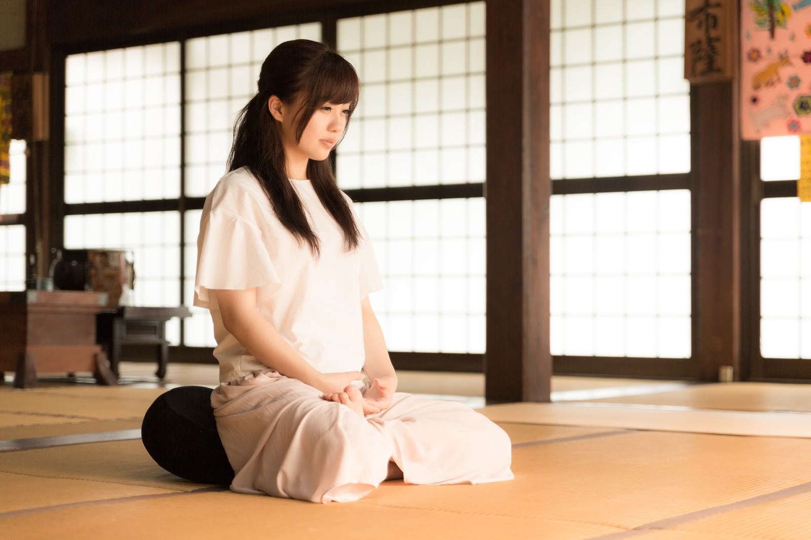 お寺の畳の間で座禅を組む若い女性［モデル：河村友歌］