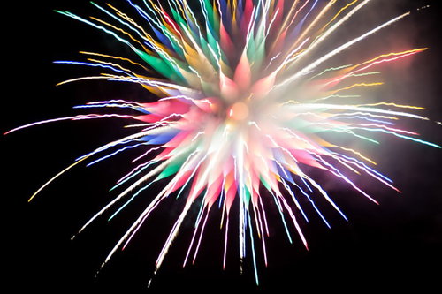 カラフルな炎色反応を起こす夜空の花火大会の光跡