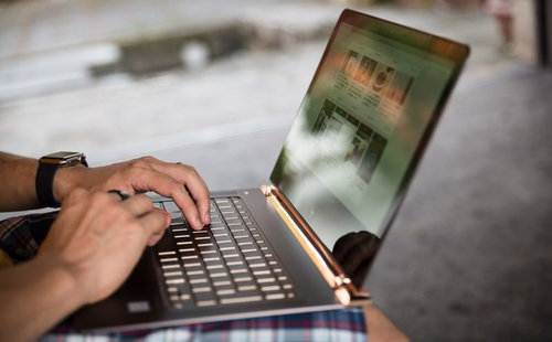 野外でノートパソコンを操作しながらブログを更新中