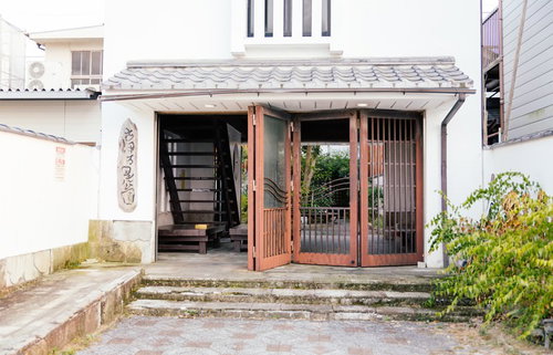 古伊万里公園の入口に立つ朱塗りの木製扉と白い漆喰壁