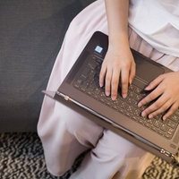 ソファーに座りノートパソコンでタイピングするライターの写真