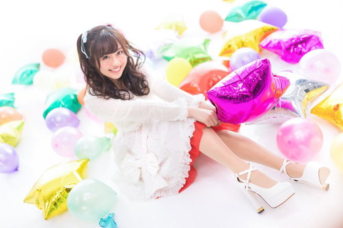 カラフルな風船に囲まれるツインテール姿の女性アイドル