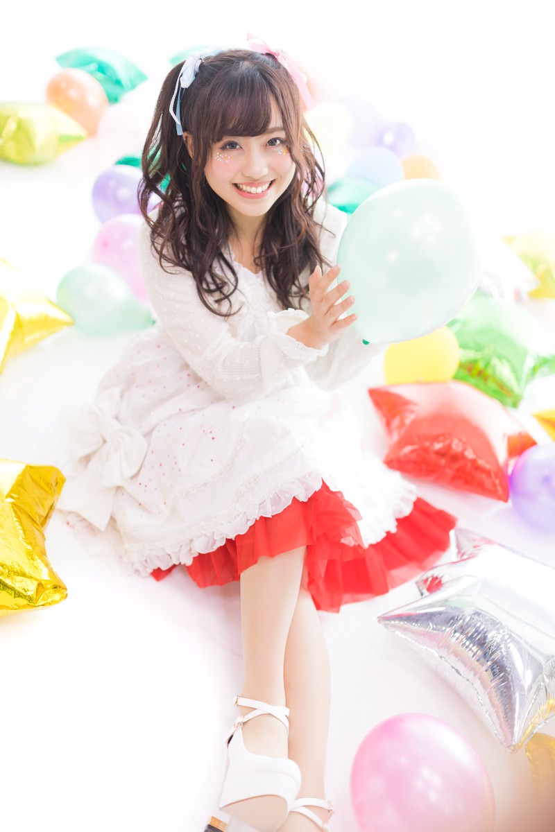 白いドレスとツインテールの女性アイドルがカラフルな風船に囲まれて笑顔を見せている［モデル：河村友歌］