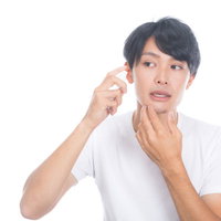 化粧水を頬に噴射するスキンケアをする男性の写真
