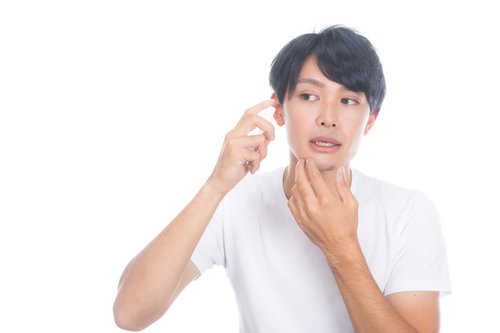 化粧水を頬に噴射するスキンケアをする男性