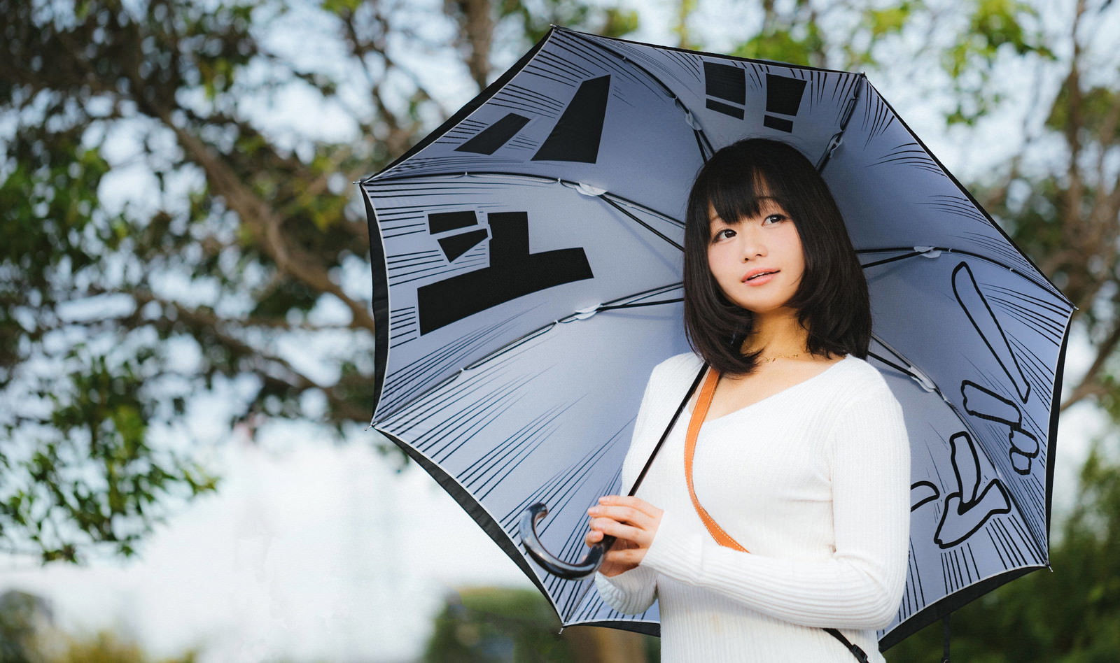 グレーの傘を持ち上空を見つめる白いニット姿の黒髪女性［モデル：茜さや］
