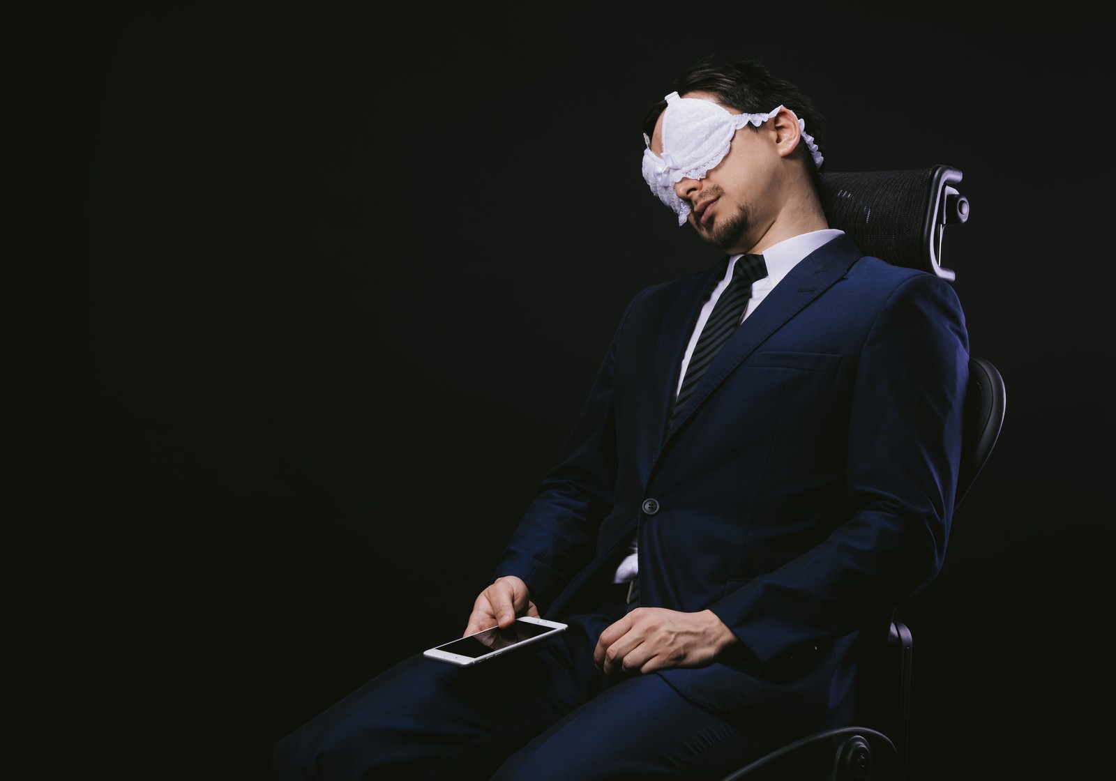 椅子でうたた寝をするスーツ姿の男性［モデル：Max_Ezaki］