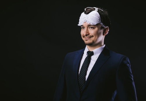 アイマスクを装着しながら目覚めるビジネスマン