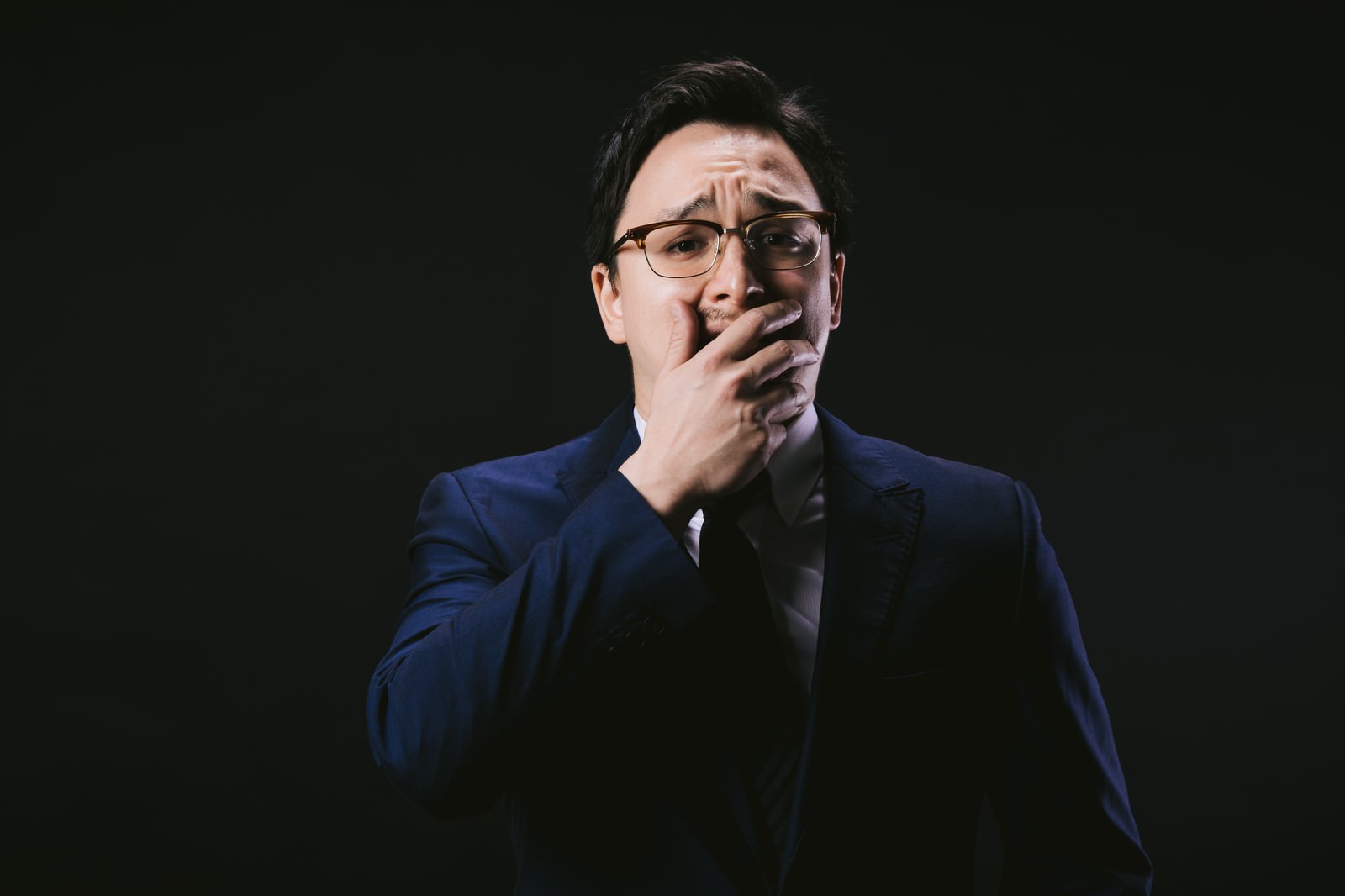 両手で顔を覆って絶望している表情のスーツ姿の男性［モデル：Max_Ezaki］