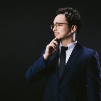 考えるフリして立ちながら寝ています。ヴィレッジヴァンガードのスーツ姿の男性の写真