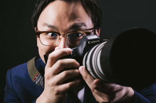 望遠レンズで狙うゲス顔カメラマン男性の怪しい表情