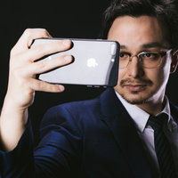 スマホで状況証拠を撮るスーツ姿のエージェント男性の写真