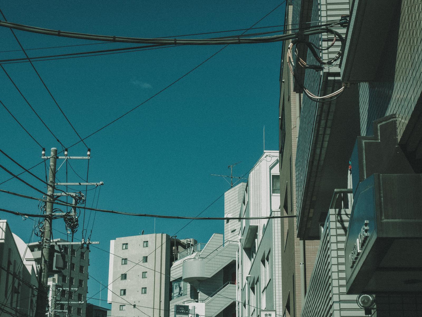 電線と電柱が交差する都市の路地
