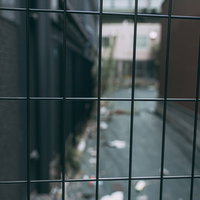 ゴミが散らかる路地裏のワイヤーフェンス越しの風景の写真