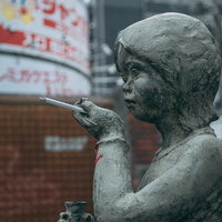 銅像に紙タバコを持たせるマナーの悪いイタズラの一幕の写真