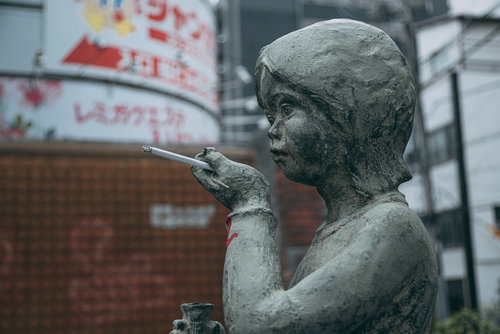 銅像に紙タバコを持たせるマナーの悪いイタズラの一幕