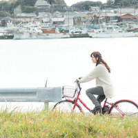 漁港を背景に自転車で出かける女性、房総半島のサイクリングの写真