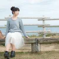 海が一望できる岬のベンチに座る若い女性のリラックス風景の写真