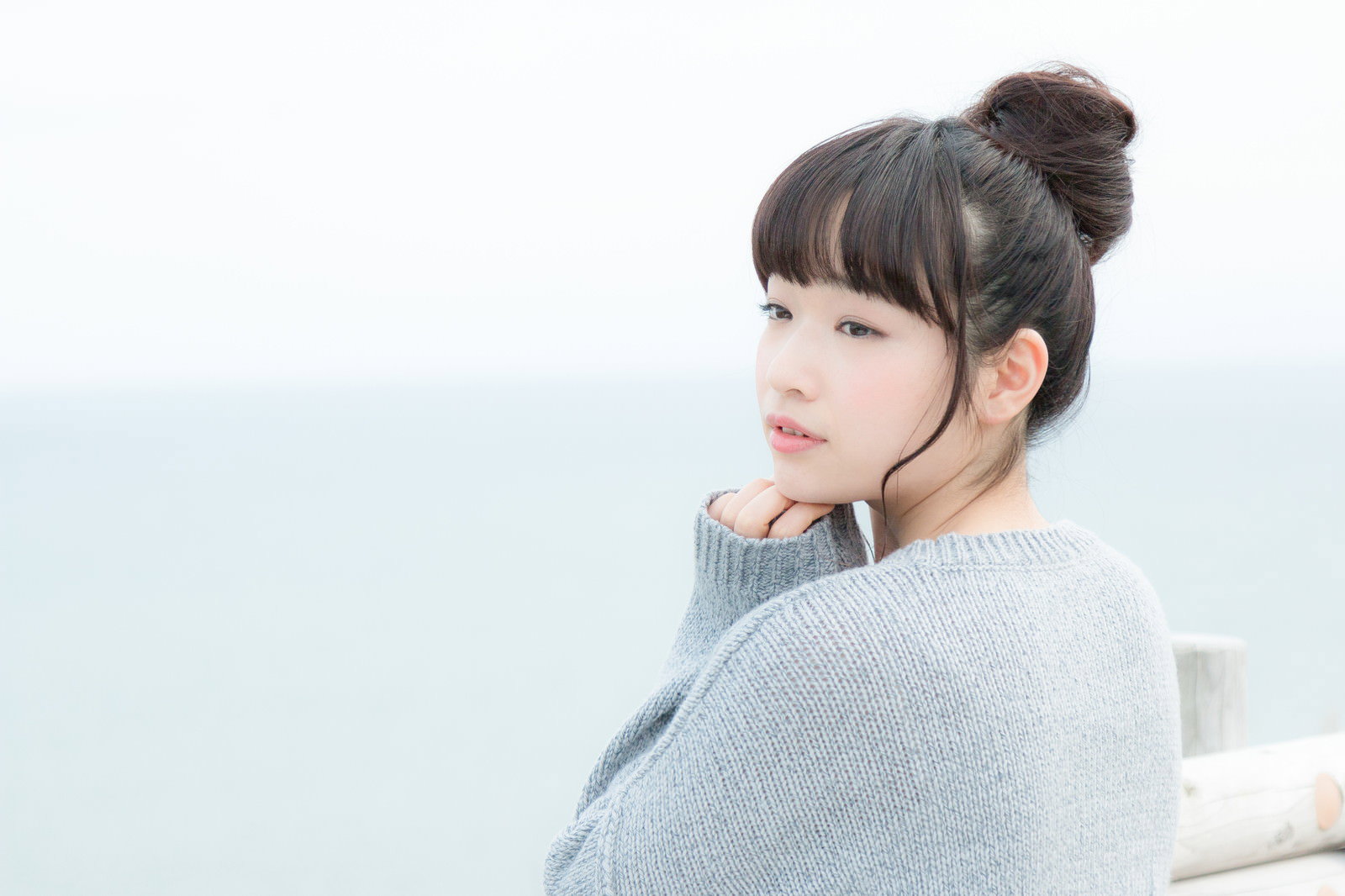 高台から海を眺める女性が後ろ姿で立っている［モデル：渡辺友美子］