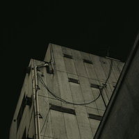 見上げるビルの外壁と配管の写真